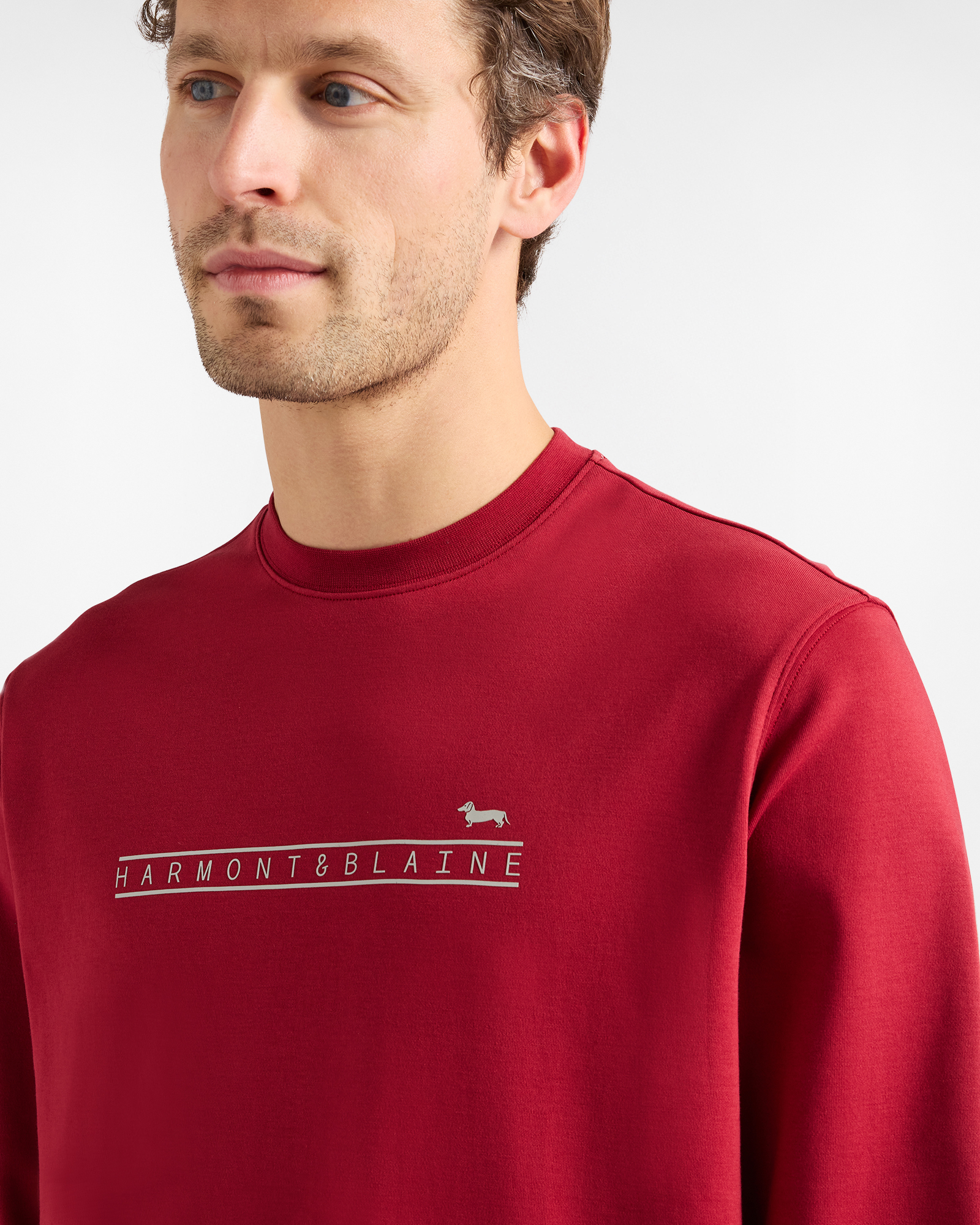 Man wearing a red sweatshirt with Harmont & Blaine logo on the chest.